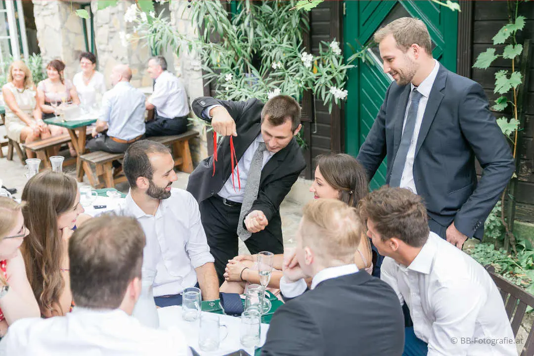 Philipp Kainz zeigt Tischzauberei mit rotem Seil für staunende Gäste im Gastgarten